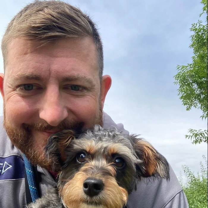 A portrait image of Warren, the owner of the business, holding a dog.